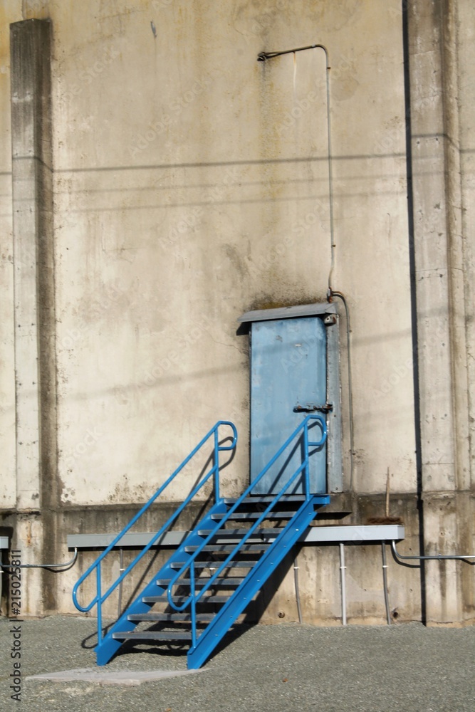 Blue painted door and stairway set in a concrete wall Blue painted door and stairway set in a concrete wall