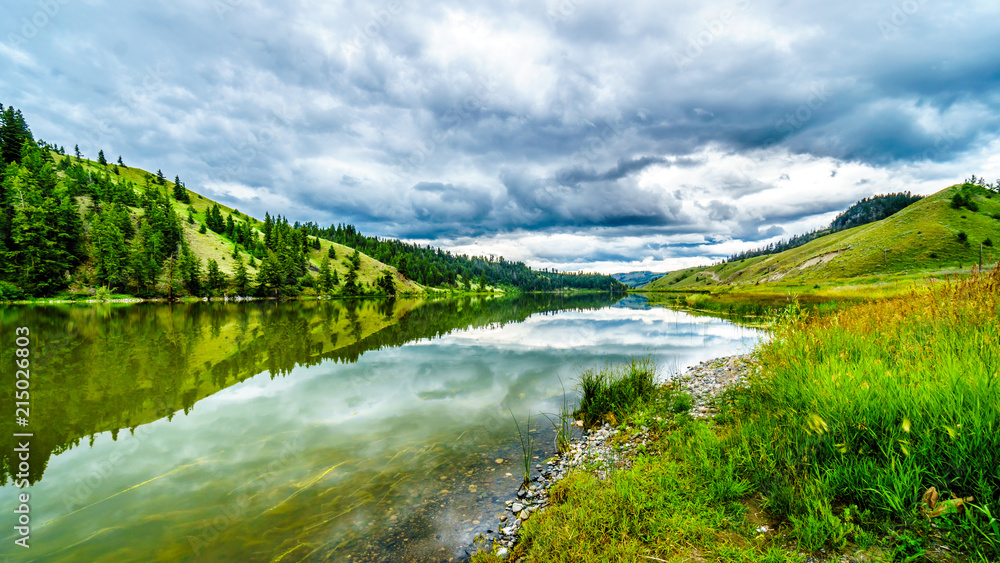 Dark Clouds and surrounding Mountains reflecting on the smooth water surface of Trapp Lake, located along Highway 5A between Kamloops and Merritt in British Columbia, Canada
