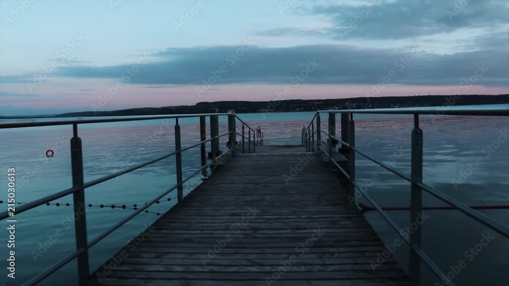 The camera is moving along a berth during sunset. The sunset gives beautiful reflections on the calm surface of Lake Constance. The camera is moving along a berth during sunset. The sunset gives beautiful reflections on the calm surface of Lake Constance.