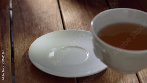 a Man places a tea cup on a wooden talbe photo