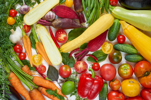 Various fresh organic vegetables on the white table  tomatoes  sliced zucchini  beet  garlic  cabbage  carrots  green beans  bell pepper basil. Cooking concept. Healthy vegetarian diet food background