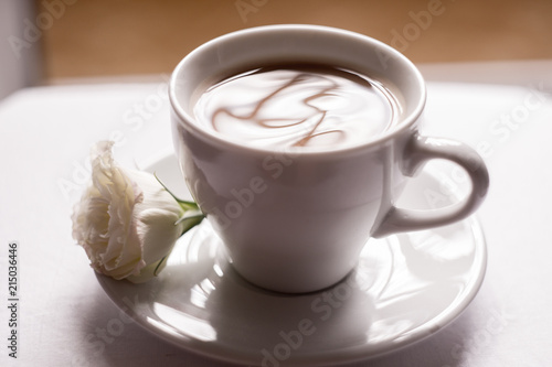 black coffee with milk in a white mug with a saucer