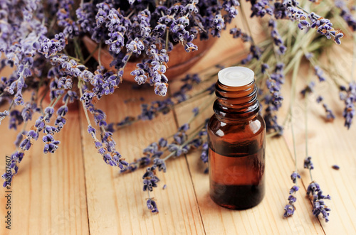 Healing lavender essential oil for beauty treatment and home deodorant. Dried purple plant flowers, dark glass dropper bottle, wooden table. Natural aromatherapy.