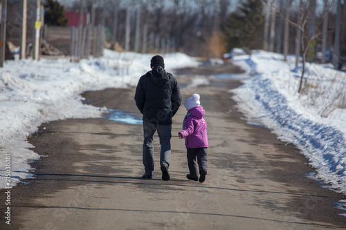 Girl with dad walking on the road in winter