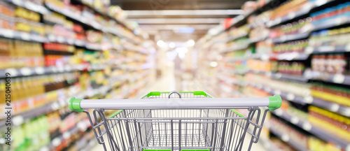 фотографія supermarket shelves aisle with empty shopping cart defocused interior blur bokeh