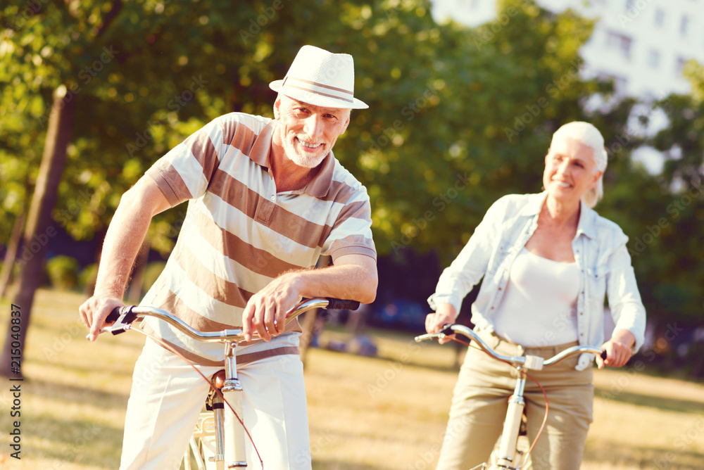Obraz premium What a lovely day. Relaxed elderly man looking into the camera with a cheerful smile on his face after spending his day outdoors and bicycling with his wife.