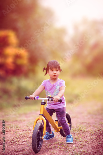 Little girl riding balance bike in the park
