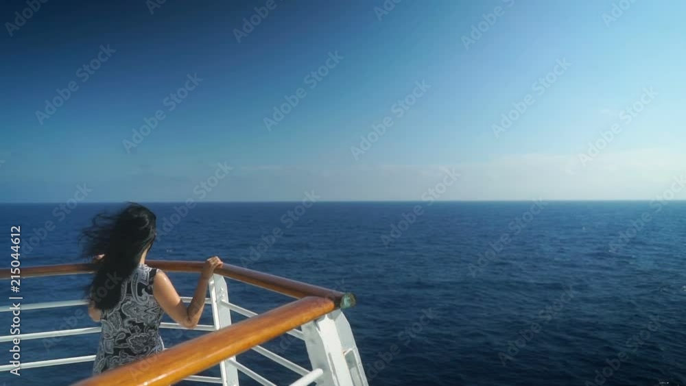 Young girl standing at front of cruise ship sailing over beautiful blue ocean. Young girl standing at front of cruise ship sailing over beautiful blue ocean.