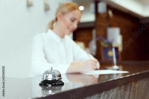 Happy female receptionist standing at hotel counter