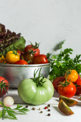 Fresh tomatoes and parsley  dill  garlic on a light background in a rustic kitchen and wooden utensils still life with a copy space