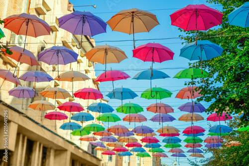 Street installation of multi-colored open umbrellas. The sky of colorful umbrellas. Background colorful urban umbrella street decoration.