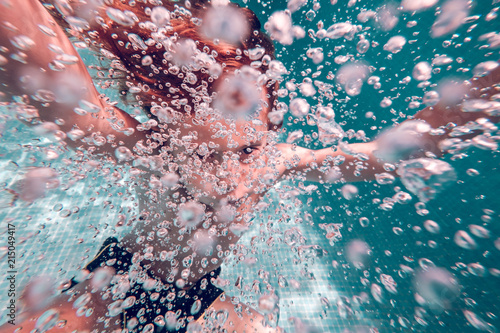 Swimming kid surrounded air bubbles