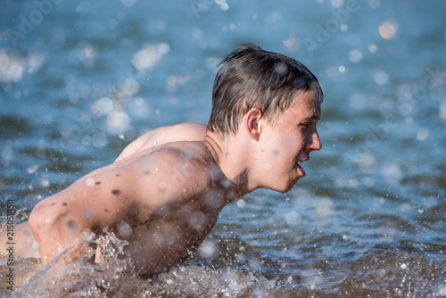 A boy teen swims in a spray of water - a concept of a beach holiday