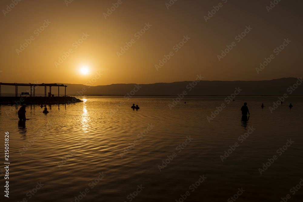 People bathing in the dead sea at sunrise