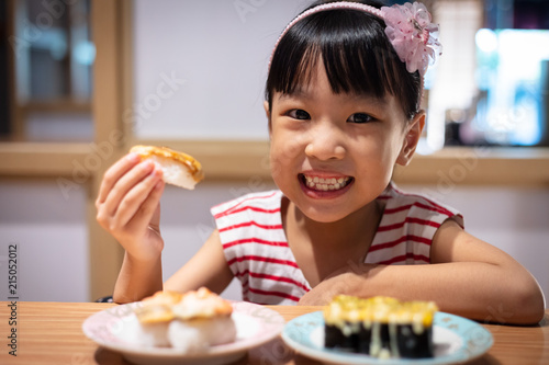 Asian little Chinese girl eating sushi