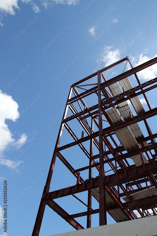 A framework of a new building being built with a blue sky surrounding it. A framework of a new building being built with a blue sky surrounding it.