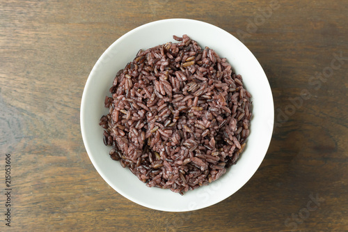 A Cooked rice berry ,Whole grain rice Thai black jasmine rice in bowl on wood table.