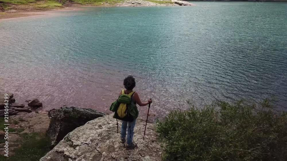 woman hiker looking at Lake Estaens in the Pyrenees mountains. woman hiker looking at Lake Estaens in the Pyrenees mountains.