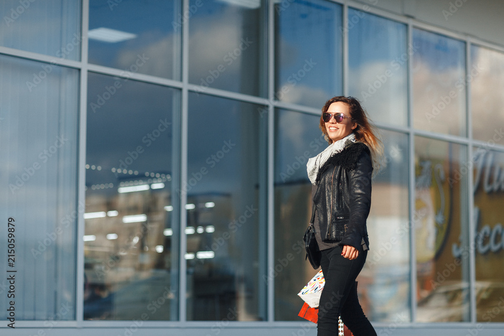 A beautiful woman walks through the city on shopping, she is very happy of purchases in the period sales. Concept: fashion, shopping, happiness and fashion bloggers