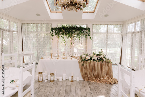 The table of the groom and bride in white color and with golden details and also is a lot of beautiful flowers