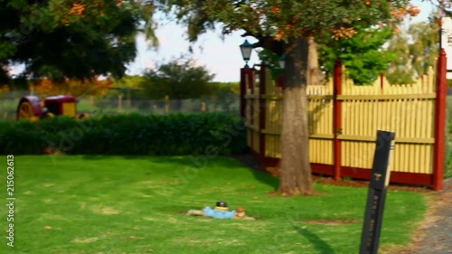 Woman in black dress walking away from camera in rural Cadell on The Murray, Australia. Day time, camera pans to left to reveal an old wooden cart. photo