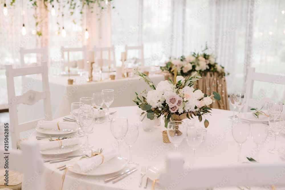 Round white table with graceful compositions of fresh flowers. Round white table with graceful compositions of fresh flowers.