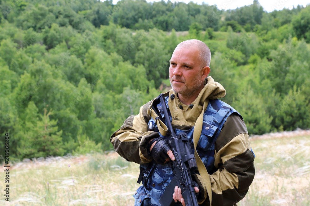 Hunting season. Male 35-40 years old hunter is standing with a firearm in the forest.