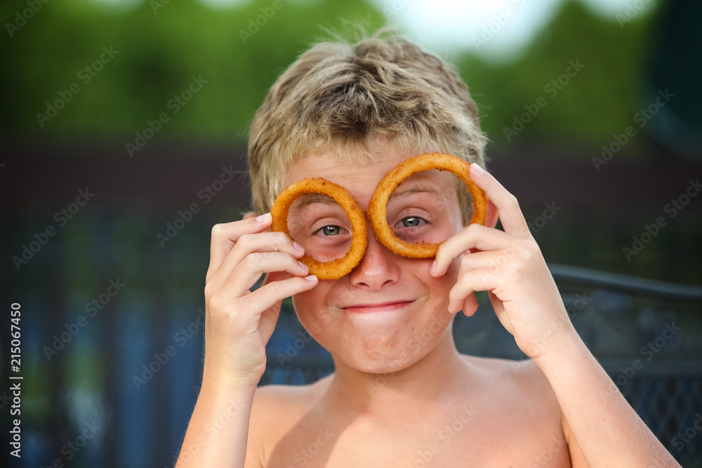 Funny boy looking through his onion rings for glasses sitting at a pool snack bar
