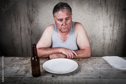 Fotografía Depressed man looking down at his empty plate and beer