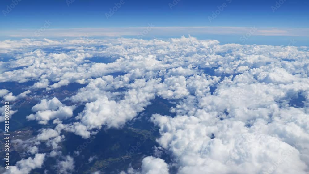 Flying over picturesque white clouds on the deep blue sky. Beautiful moving clouds view from airplane window. Traveling through clear blue cloudscape. Flying over picturesque white clouds on the deep blue sky. Beautiful moving clouds view from airplane window. Traveling through clear blue cloudscape.