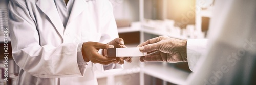 Cropped image of patient hand taking box from pharmacist photo