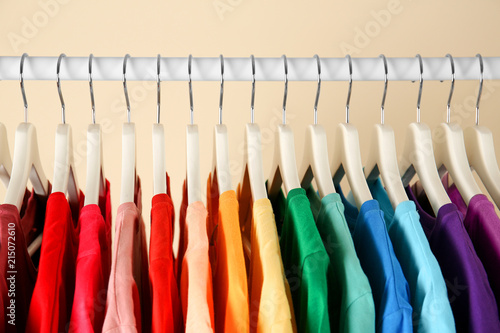 Many t-shirts hanging in order of rainbow colors, closeup
