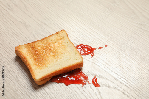 Overturned toast bread with jam on floor