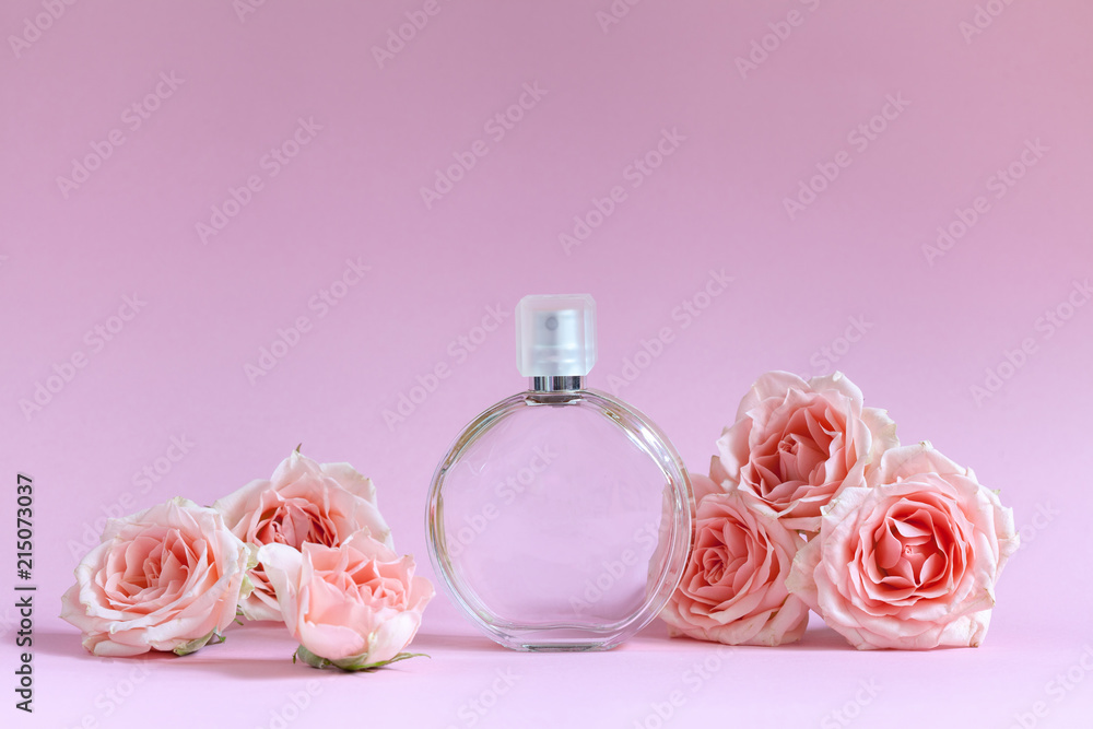 Perfume bottle surrounded by pink roses on a pink background. Makeup template Perfume bottle surrounded by pink roses on a pink background. Makeup template