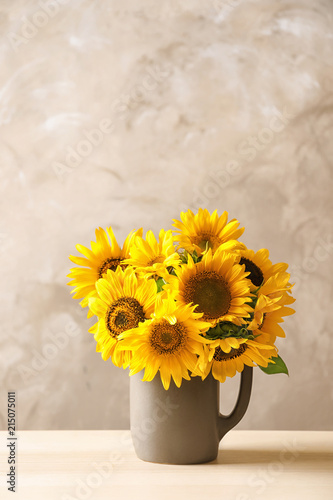 Jug with beautiful yellow sunflowers on table