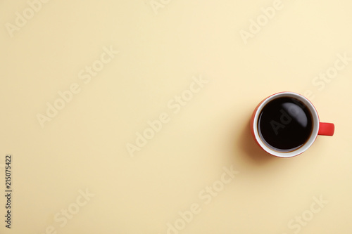 Ceramic cup with hot aromatic coffee on color background, top view