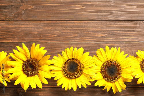 Beautiful bright sunflowers on wooden background, top view