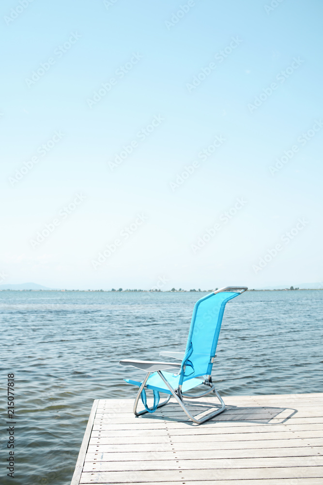 Fototapeta premium blue deck chair on a pier