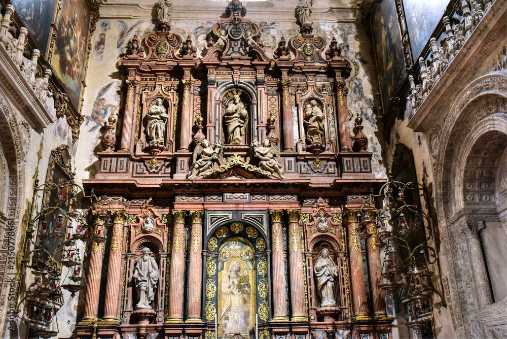Ornate side chapel of the Virgin of Antigua with red covered pews at the Seville Cathedral
