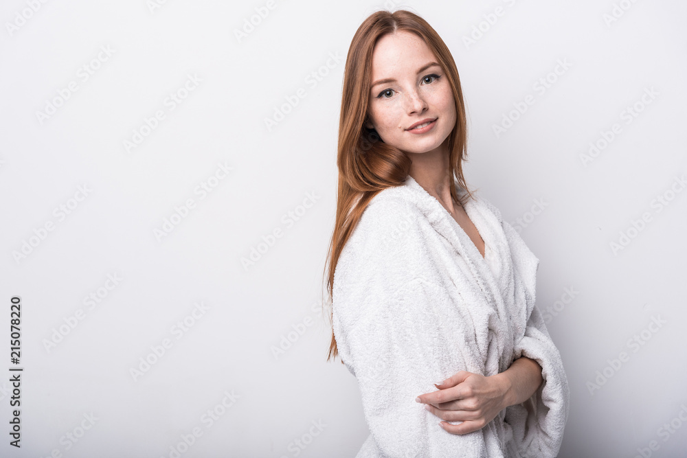 Beautiful red-haired girl in a white bathrobe on a light background Beautiful red-haired girl in a white bathrobe on a light background
