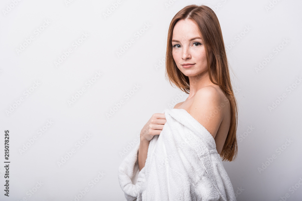 Beautiful red-haired girl in a white bathrobe on a light background Beautiful red-haired girl in a white bathrobe on a light background