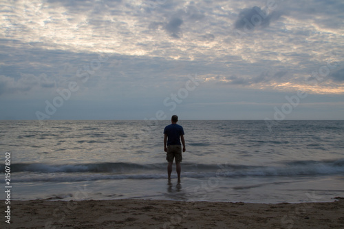 an alone and isolated man on a beach at sunset 