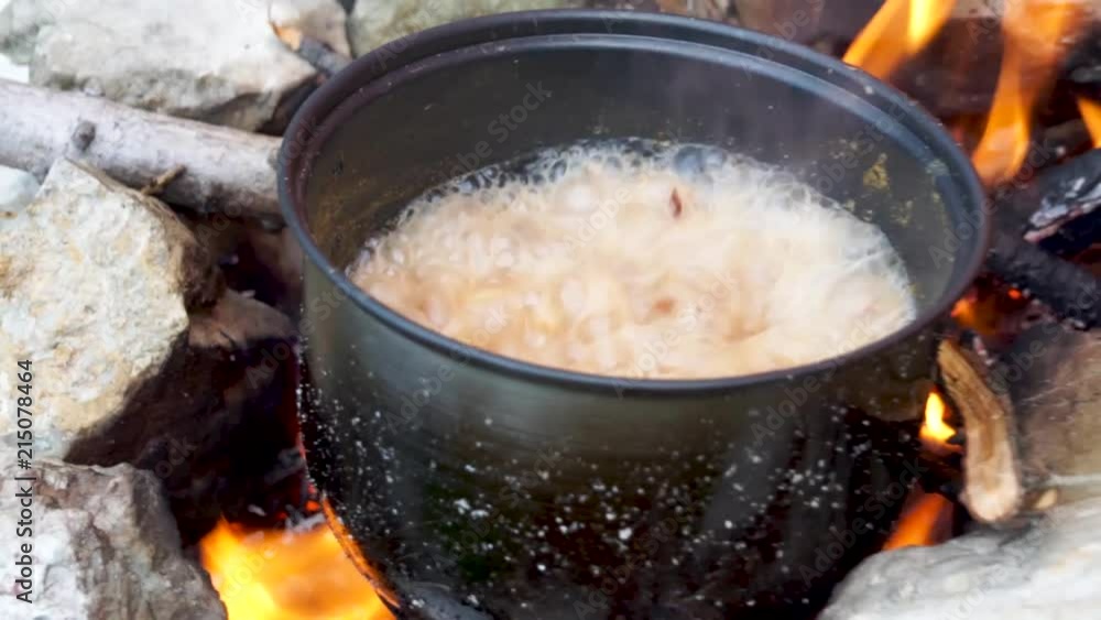 Pot with soup crazily boiling on a rough, firsthand, campfire Pot with soup crazily boiling on a rough, firsthand, campfire