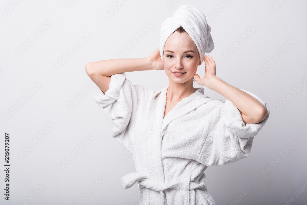 Beautiful red-haired girl in a white bathrobe with a towel on her head on a light background Beautiful red-haired girl in a white bathrobe with a towel on her head on a light background