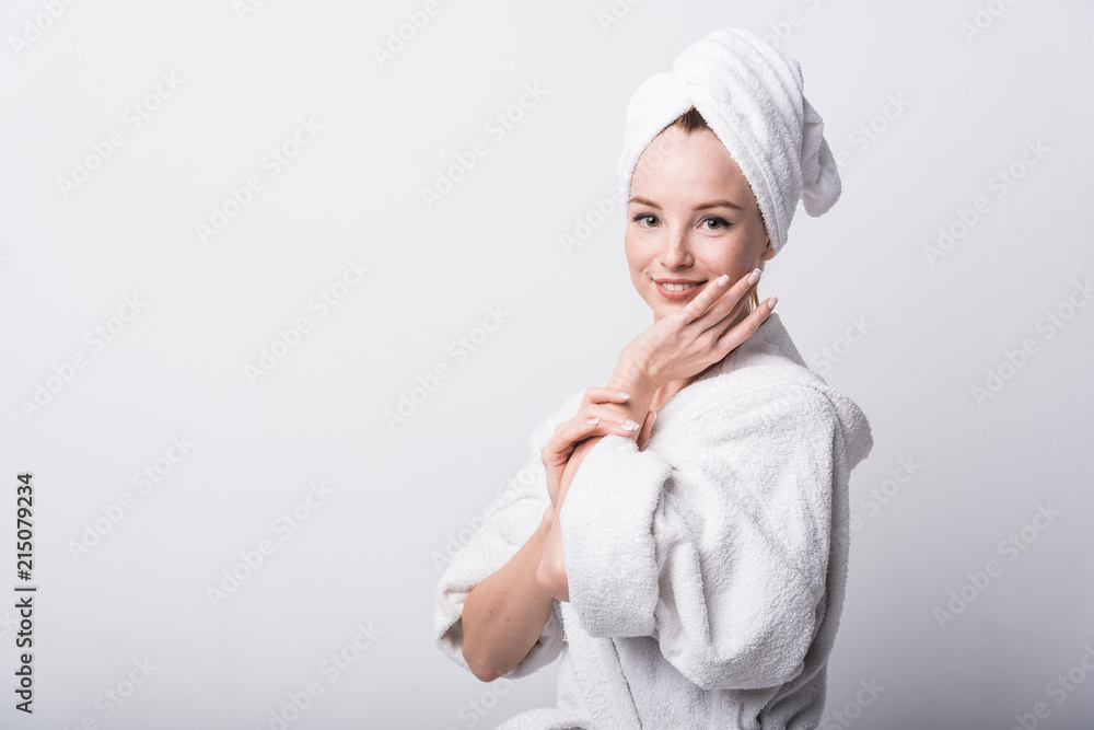 Beautiful red-haired girl in a white bathrobe with a towel on her head on a light background Beautiful red-haired girl in a white bathrobe with a towel on her head on a light background