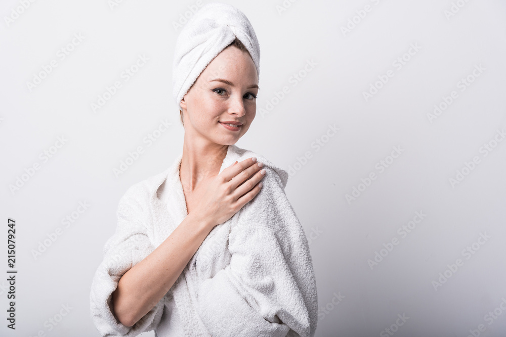 Beautiful red-haired girl in a white bathrobe with a towel on her head on a light background Beautiful red-haired girl in a white bathrobe with a towel on her head on a light background