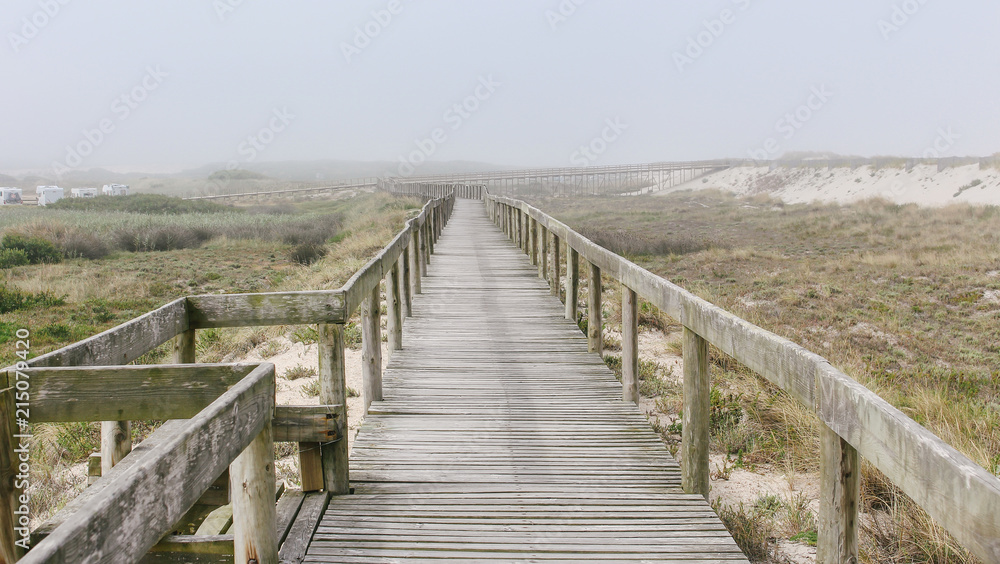 Wooden footbridge of Costa Nova beach in a foggy morning. Aveiro, Portugal Wooden footbridge of Costa Nova beach in a foggy morning. Aveiro, Portugal