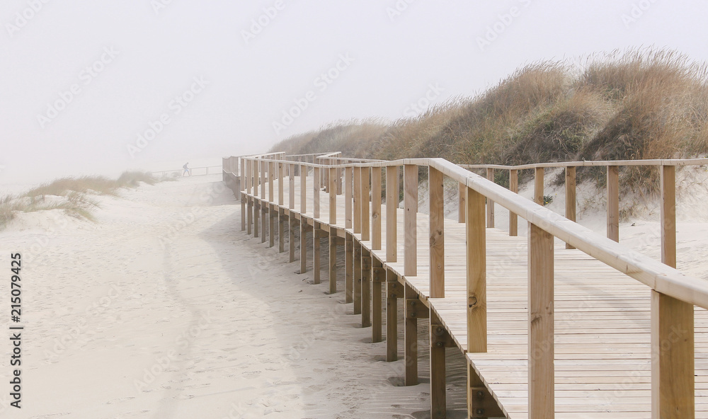 Foggy photo of wooden footbridge of Costa Nova beach in Aveiro, Portugal