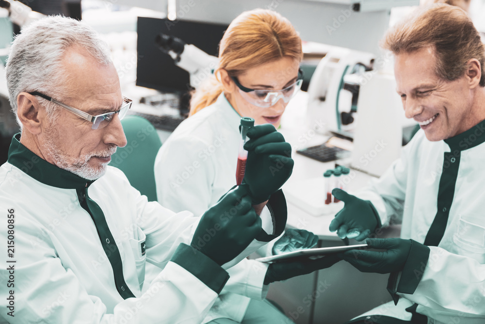 Obraz premium Test tube. Hard-working medical worker wearing glasses feeling curious while holding test tube
