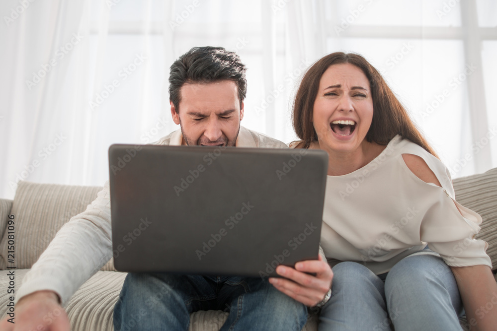 Happy couple sitting on sofa and using laptop at home Happy couple sitting on sofa and using laptop at home